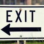 A white sign with text that says "exit" with an arrow pointing left.