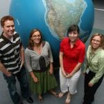 Students standing in front of a large globe.