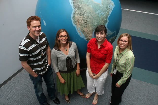 Students standing in front of a large globe.