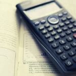 A calculator laying on top of a textbook.