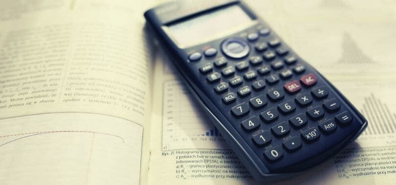 A calculator laying on top of a textbook.