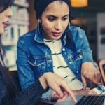 Two students sitting around a laptop applying to internships.