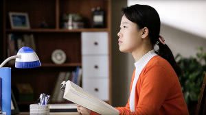 A girl holding a bible and looking far away.