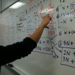 A student answers a math equation on the board.