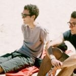 A pair of twins sitting at a beach.