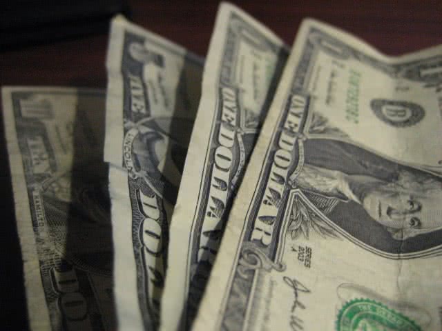 Four dollar bills stacked on each other.