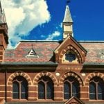 A brown college building with a clock tower on the side of the building.