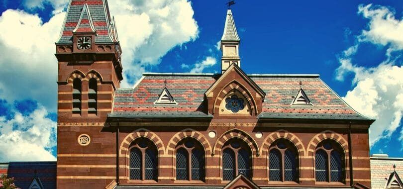A brown college building with a clock tower on the side of the building.