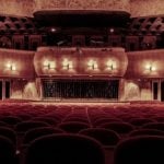 A student sitting in a dimly lit theatre.