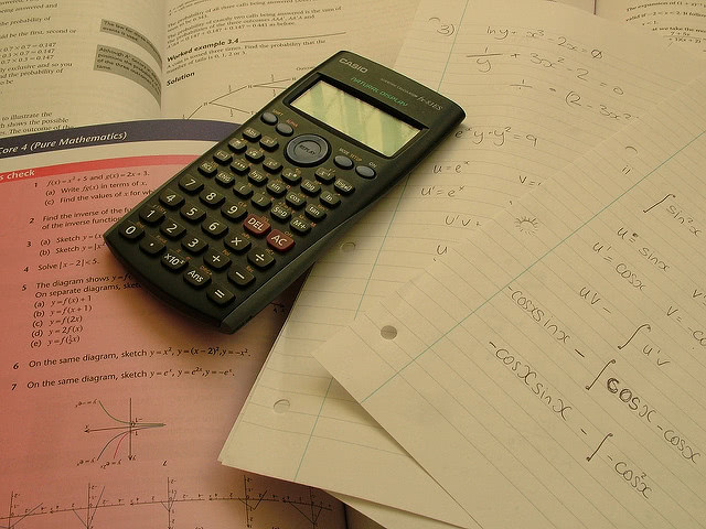 Casio calculator placed over a math book and notes.