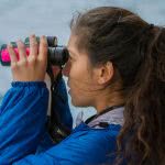 Side view of a girl looking through binoculars.