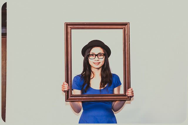 A girl holding a picture frame in front of her.