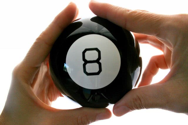 Both hands holding a number 8 billiard ball.