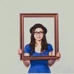 A girl holding a picture frame infront of her.