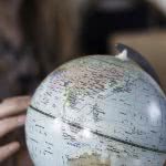 Girl's hand touching a globe figure.