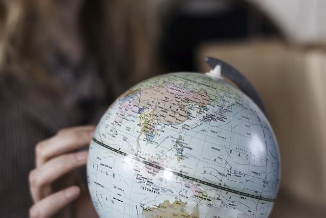 Girl's hand touching a globe figure.