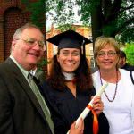 Girl on her graduation gown with her parents.