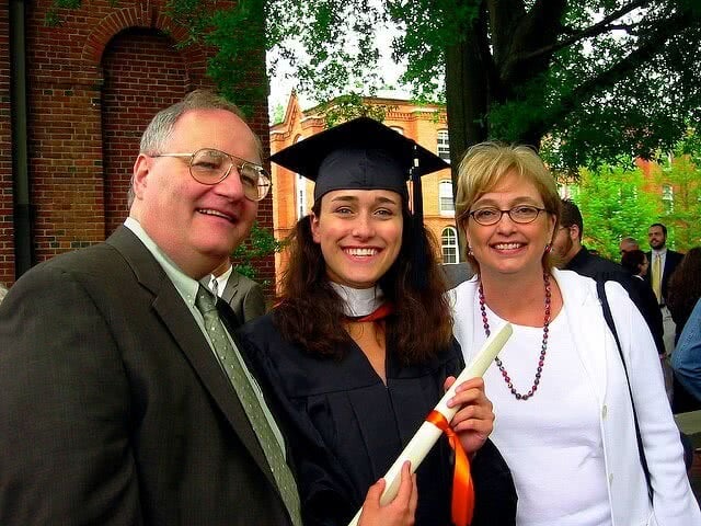 Girl on her graduation gown with her parents.