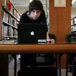 A student in the library starring at her black mac laptop.