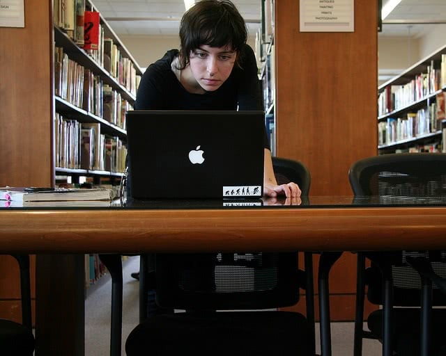 A student in the library starring at her black mac laptop.