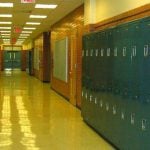 An empty high school hallway with blue lockers lining the walls.