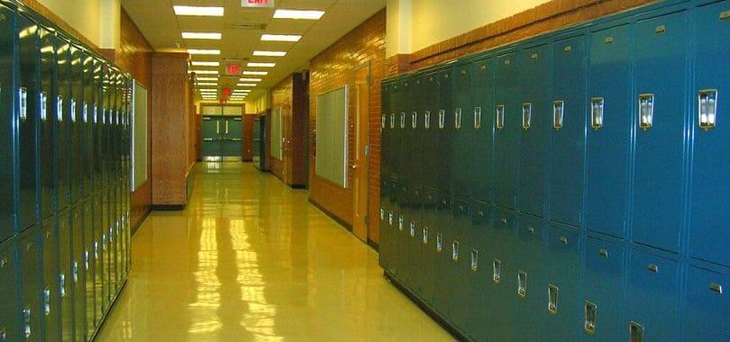 An empty high school hallway with blue lockers lining the walls.