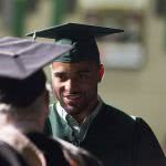 A smiling male graduate student facing the Dean.