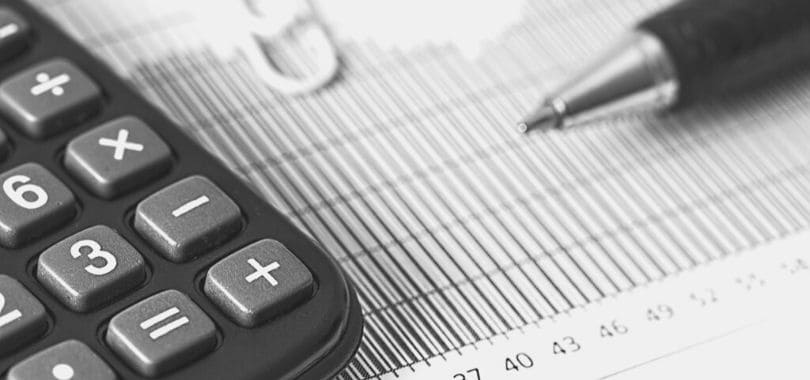A calculator and pen on top a piece of paper.