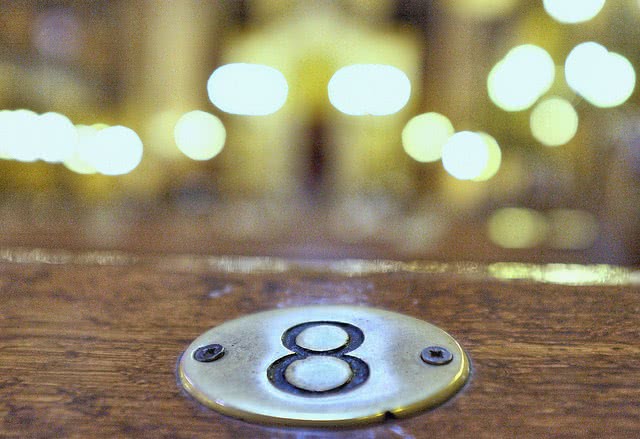 Golden plate number 8 screwed on a wooden table.