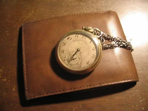 A watch on a wallet because time is money. Should you pay off student loans early?