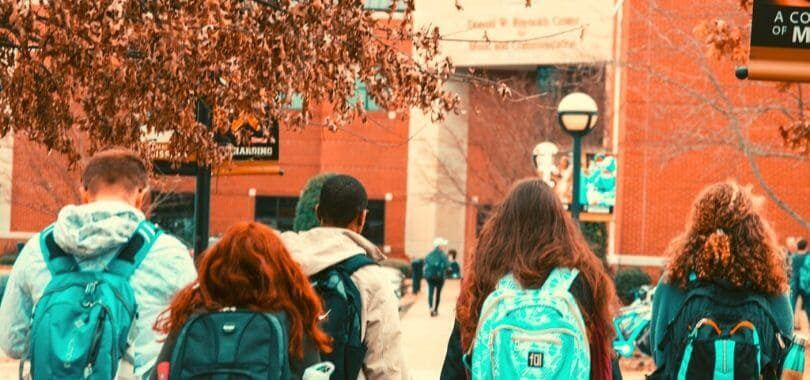 Students wearing backpacks walking on campus.