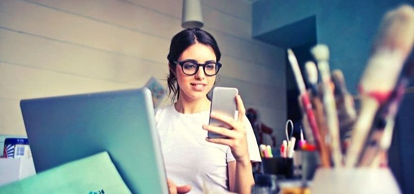 College student filing her FAFSA on her phone and laptop.