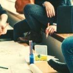 Students sitting around a table with paper and pens.