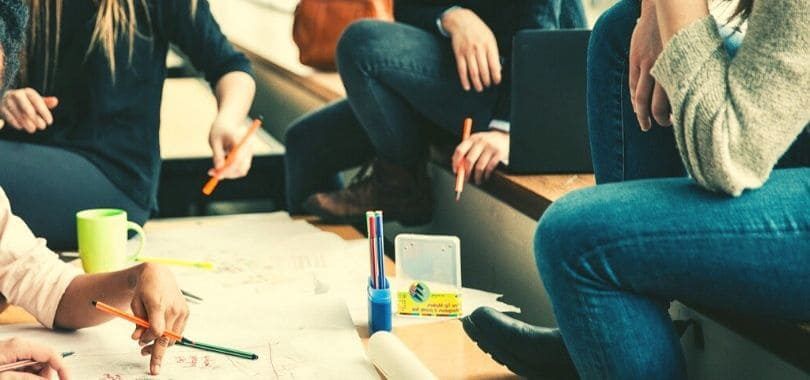Students sitting around a table with paper and pens.