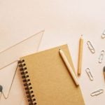 A notebook, pencils, paperclips and protractors scattered on a desk.