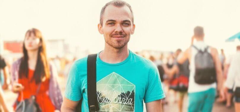 A college student on campus smiling at a camera.