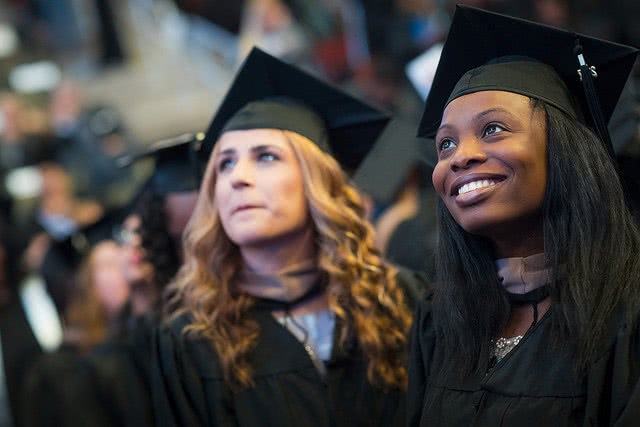 Two students at graduation have to start thinking about paying back student loans
