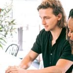 Two people sitting around a laptop.