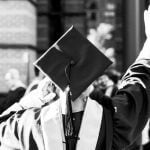 A student wearing graduation robes facing away from the camera.