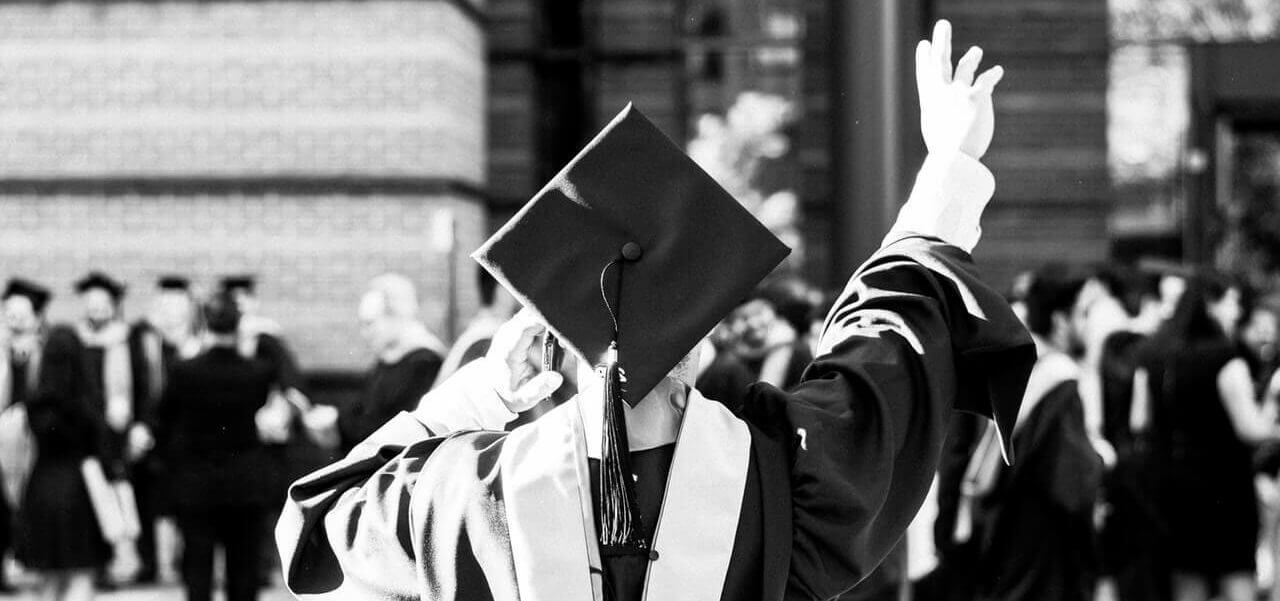 A student wearing graduation robes facing away from the camera.