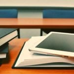 Textbooks on a desk with an iPad laying on an open textbook.