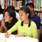 Student writing her scholarship application letters in a library