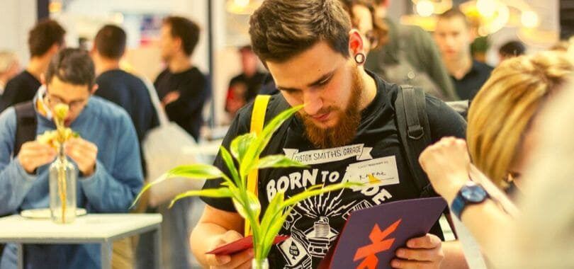 A student standing at a table looking through a folder.