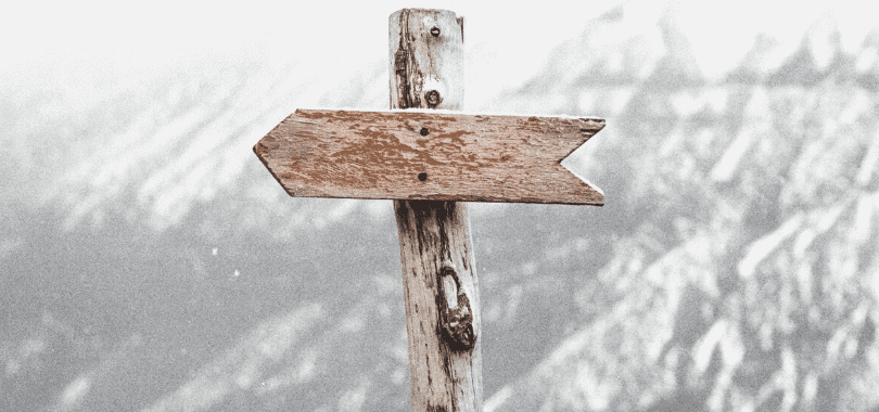 A wooden arrow on a post pointing to the left.