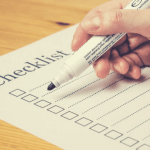 A person holding a marker against a checklist.