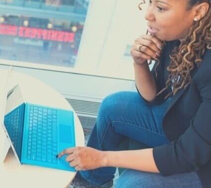 Computer scientist thinking about a problem while working on her blue laptop.