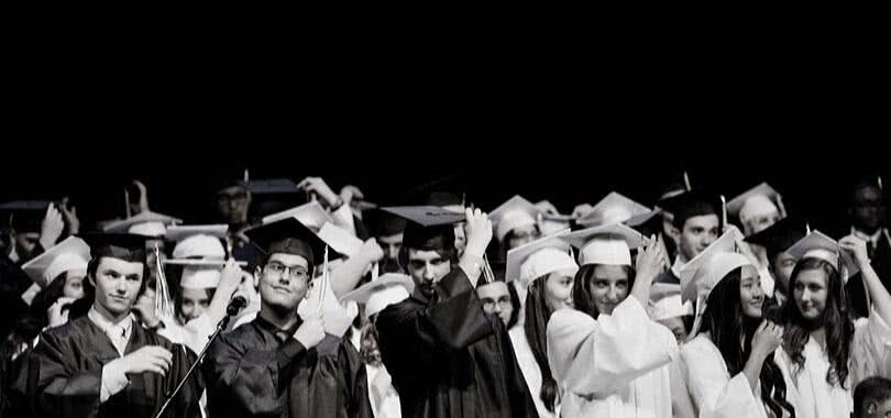 High school students at graduation, moving their tassels on their graduation caps.