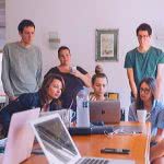 liberal arts students standing around a desk looking at a computer for a project