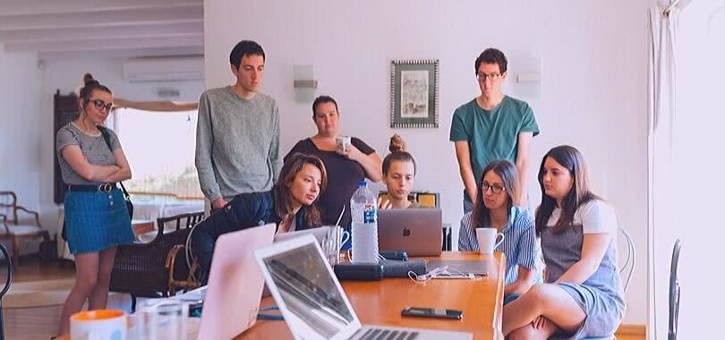 liberal arts students standing around a desk looking at a computer for a project