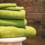 Green towels and cloths on a stool in a college dorm room.